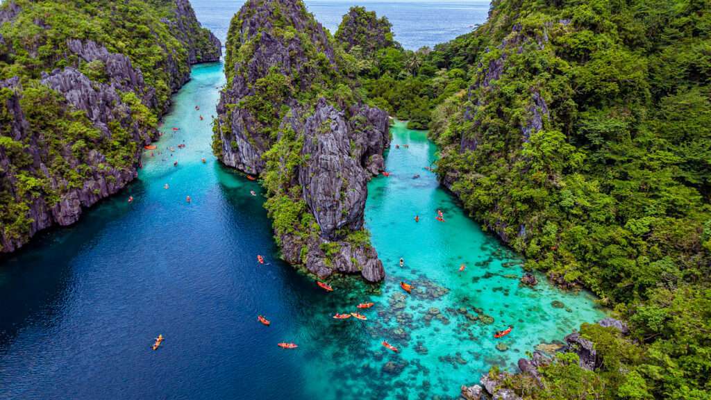 Kayakers paddling through the narrow rock entrance into Big Lagoon, El Nido