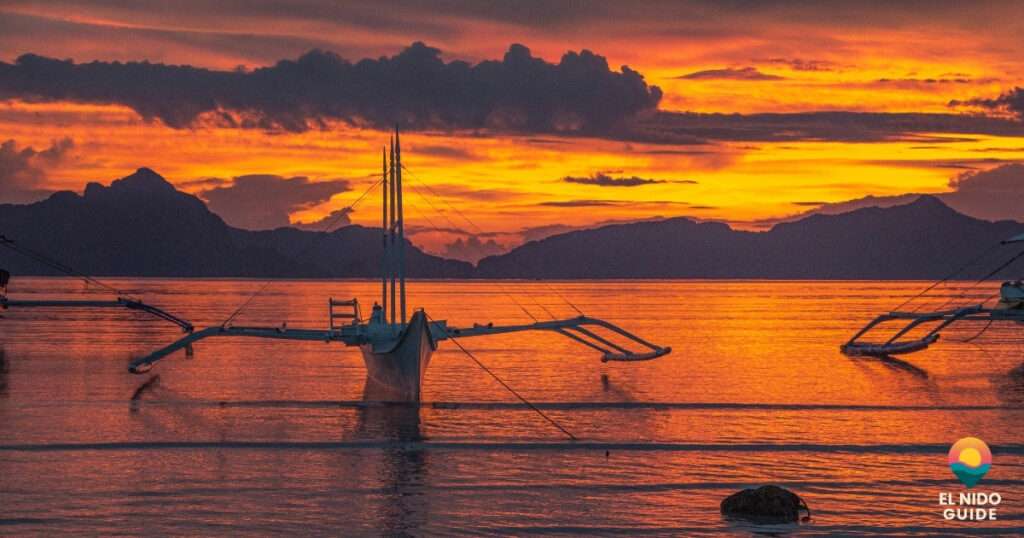 Tour boats lined up along El Nido's shore at golden hour