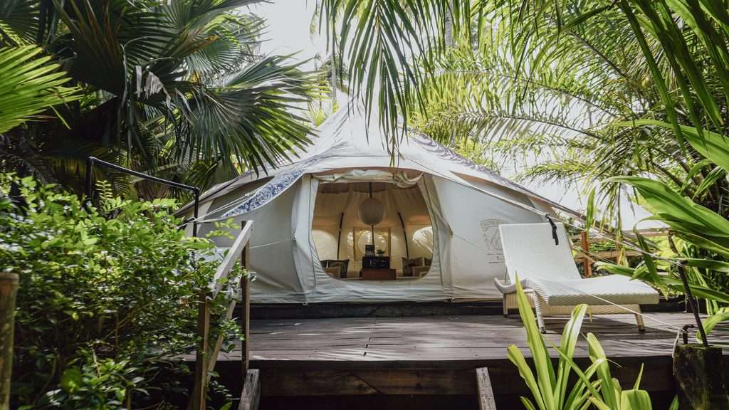 Canvas glamping tent with a timber deck, framed by tropical planting at Nacpan Beach, El Nido