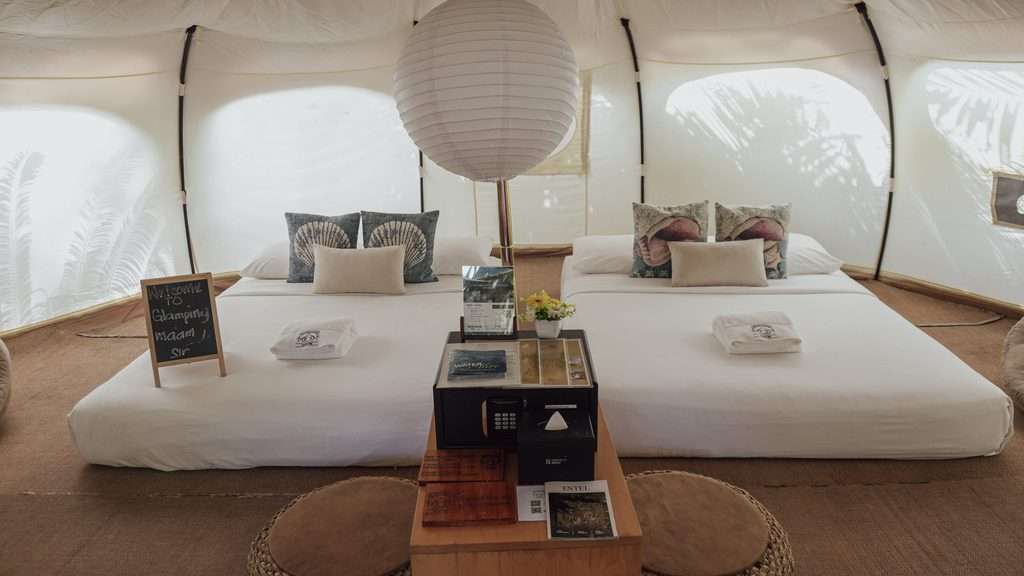 Interior of a luxury glamping tent at Nacpan Beach with two queen beds and a paper pendant light