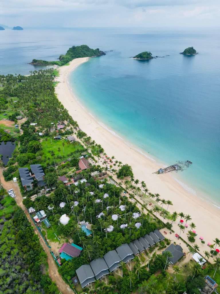 Aerial view of the four-kilometer curve of Nacpan Beach in El Nido with islands offshore