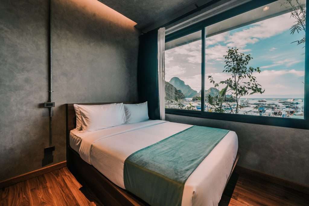 Queen Room with Sea View at Z Garden Hotel El Nido with a wide window framing the limestone cliffs