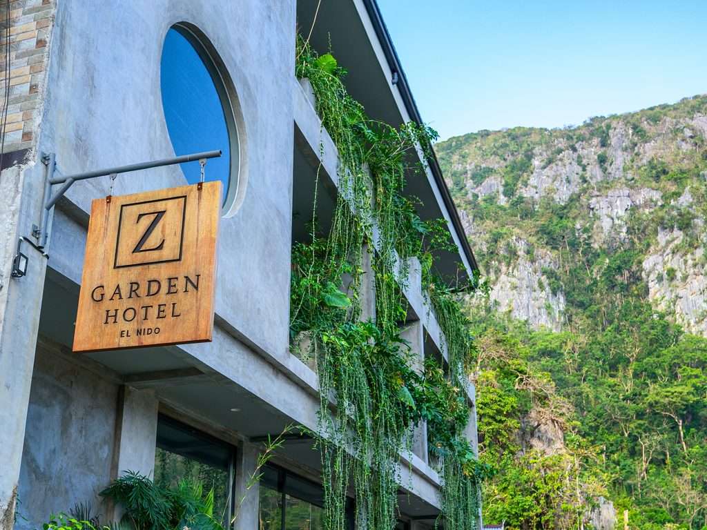 Entrance to Z Garden Hotel El Nido on a town street with Taraw Cliff rising behind